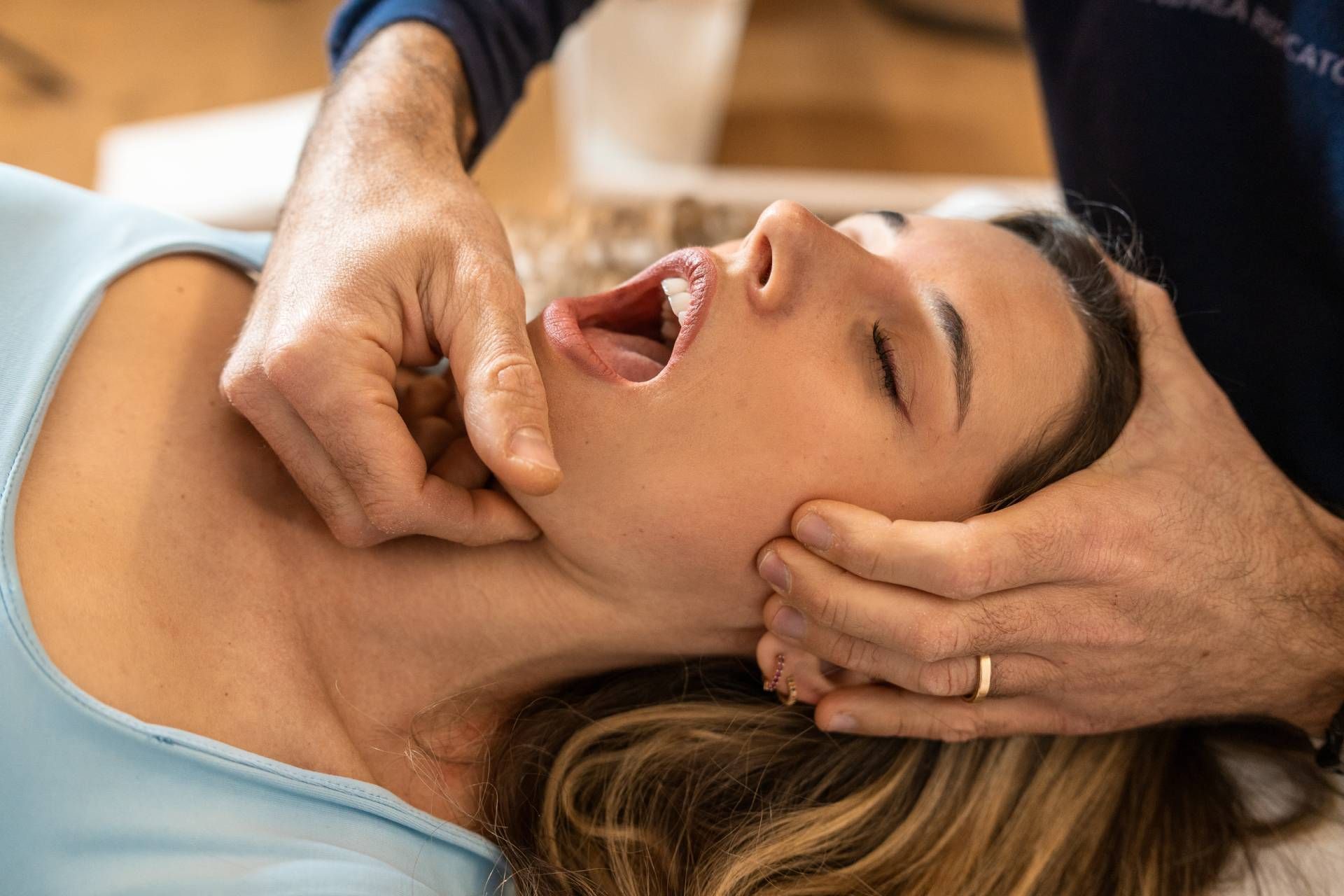 Woman receiving a jaw adjustment from a therapist in a clinic setting