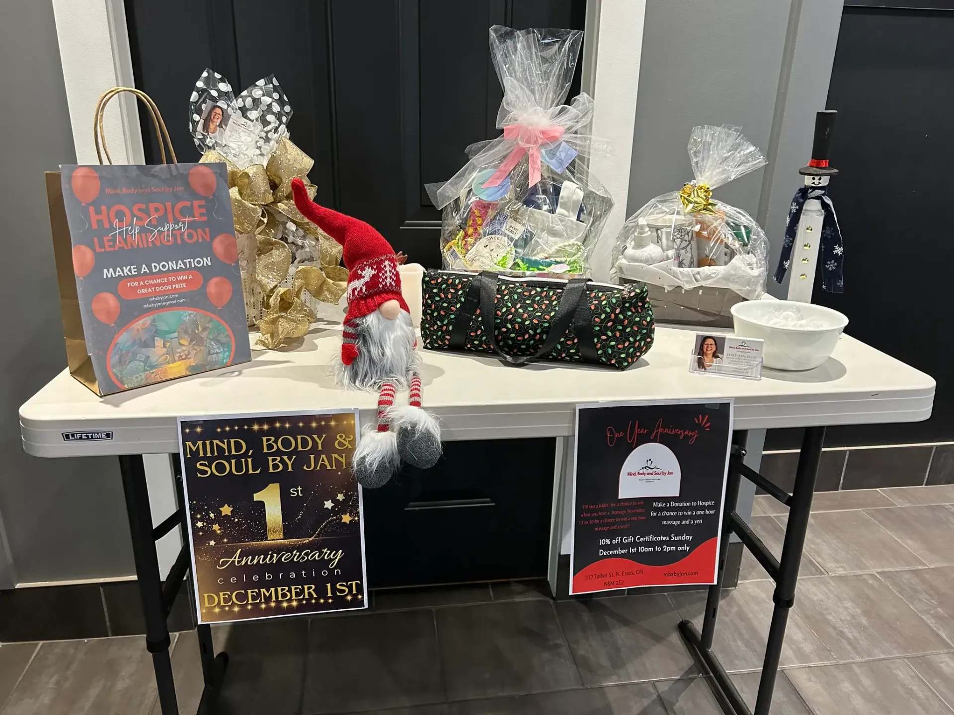 Holiday gift display on a table with wrapped baskets, festive signs, and small Santa decorations