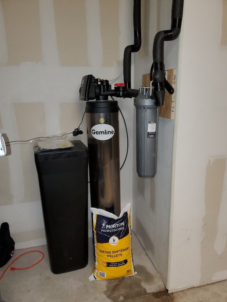 A water filter is sitting next to a bag of water in a room.