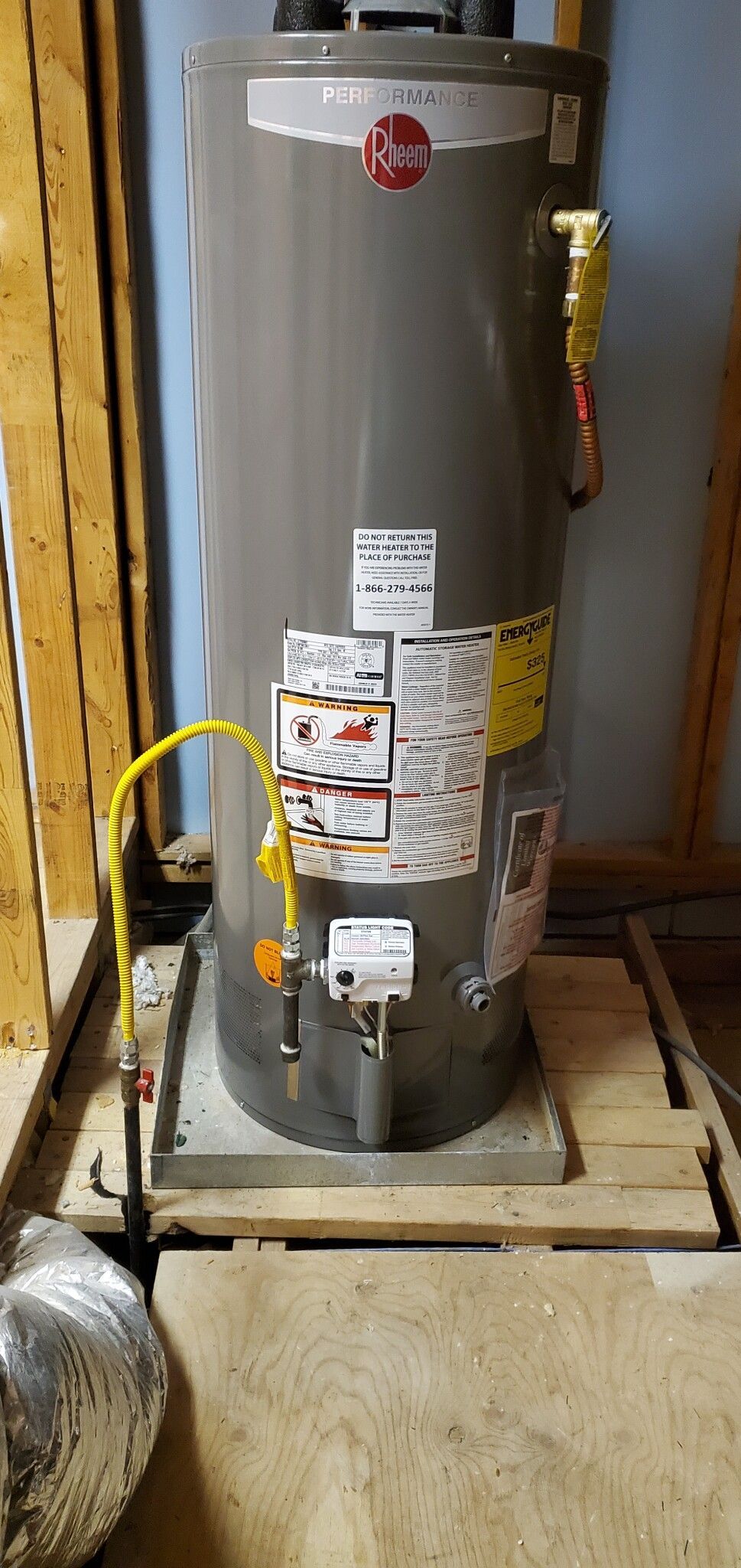 A gas water heater is sitting on top of a wooden pallet.