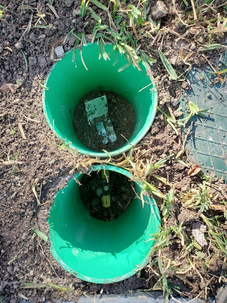 Two green buckets filled with dirt are sitting on the ground.