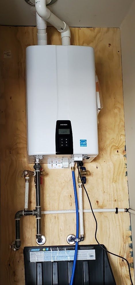 A white water heater is hanging on a wooden wall.