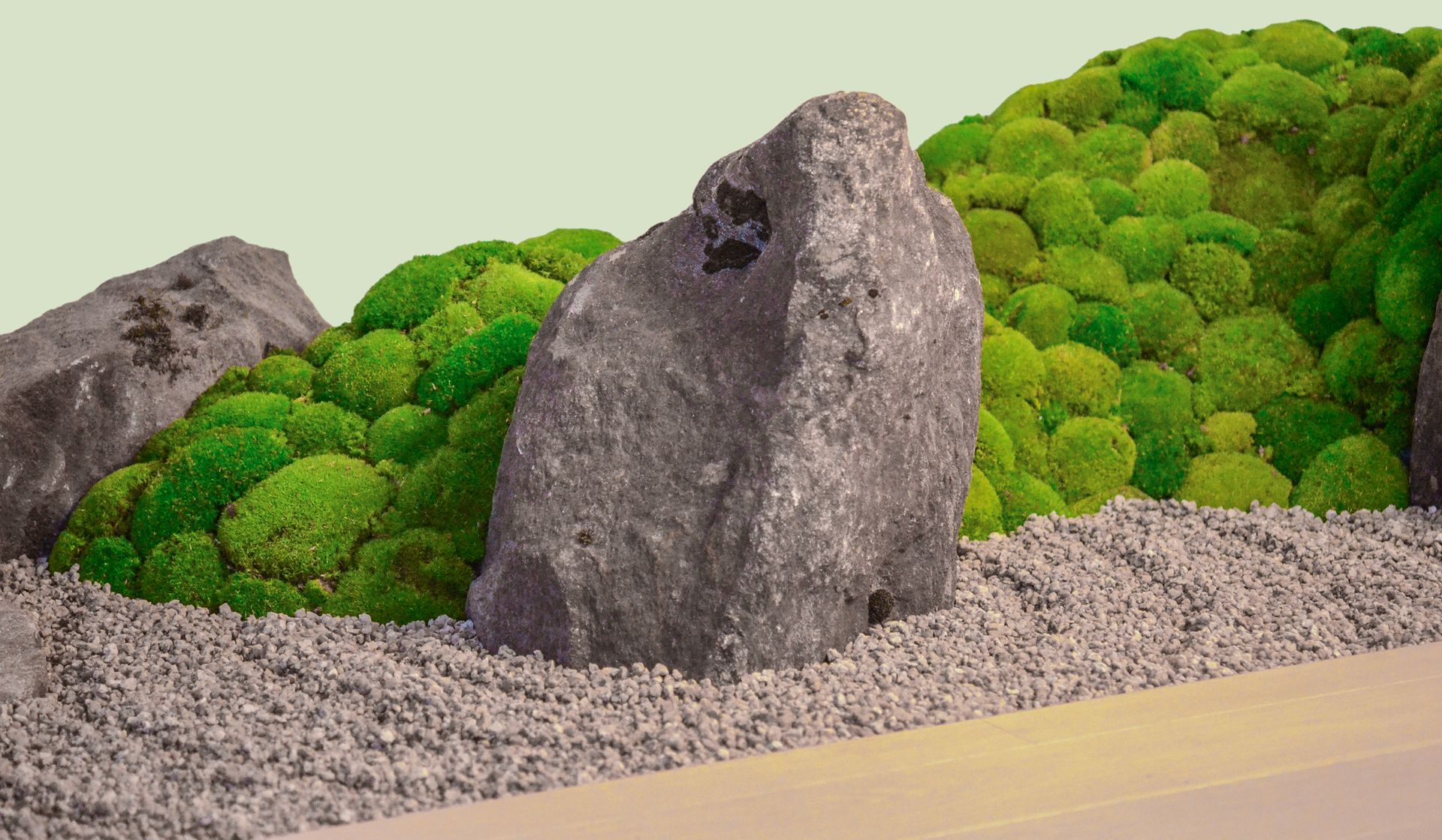 Una roccia circondata da muschio e ghiaia in un'allestimento giapponese.