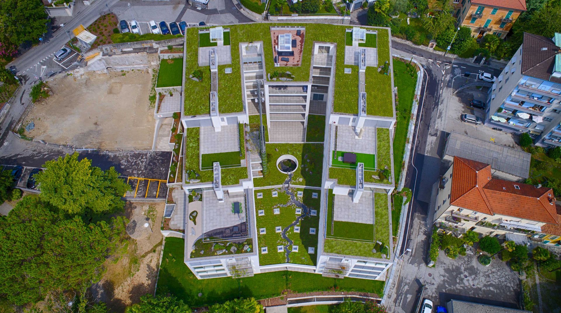 Una vista aerea di un grande edificio con un tetto verde circondato da alberi.