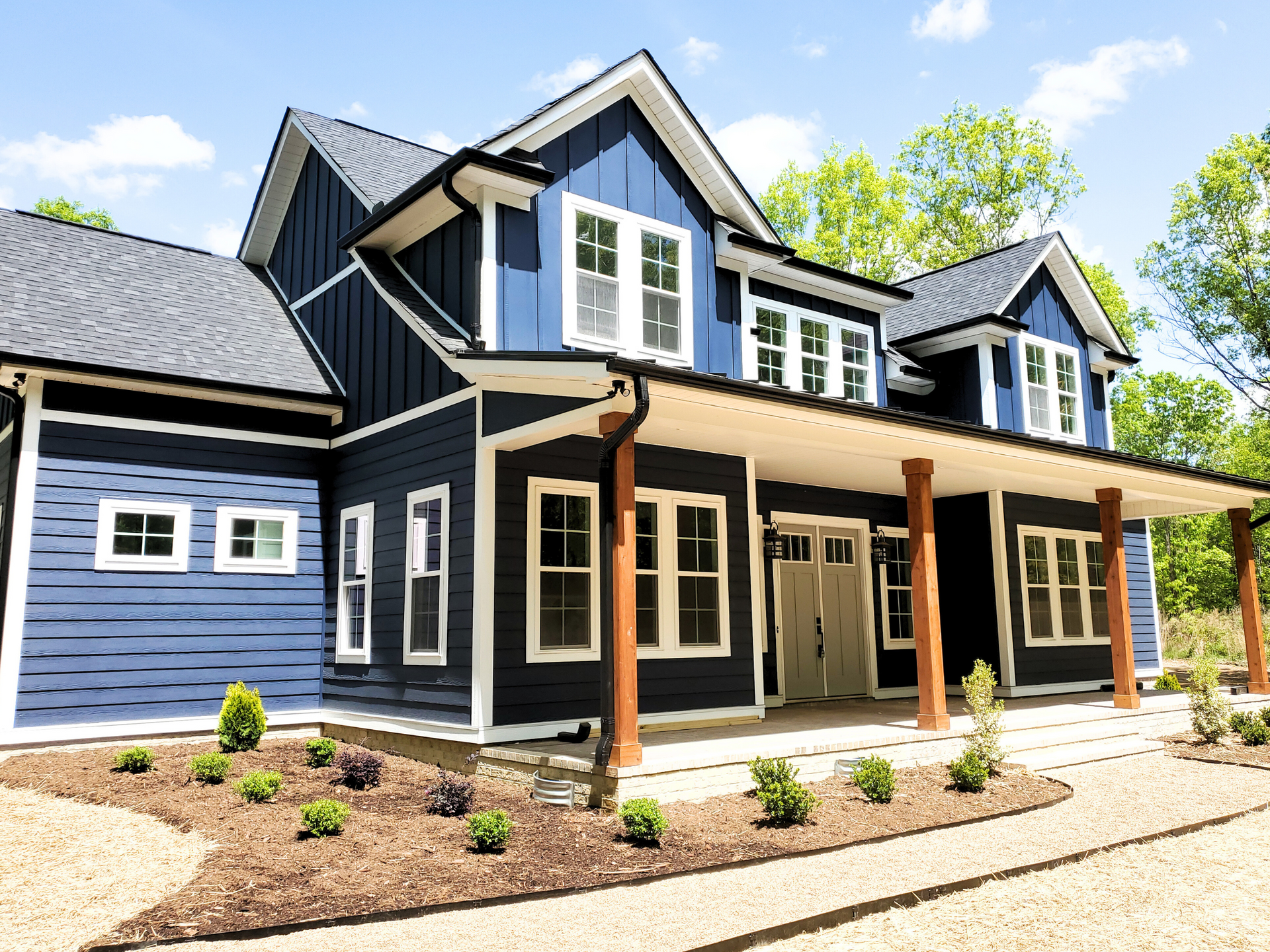 Modern two-story navy house with white trim, covered porch, and landscaped front yard