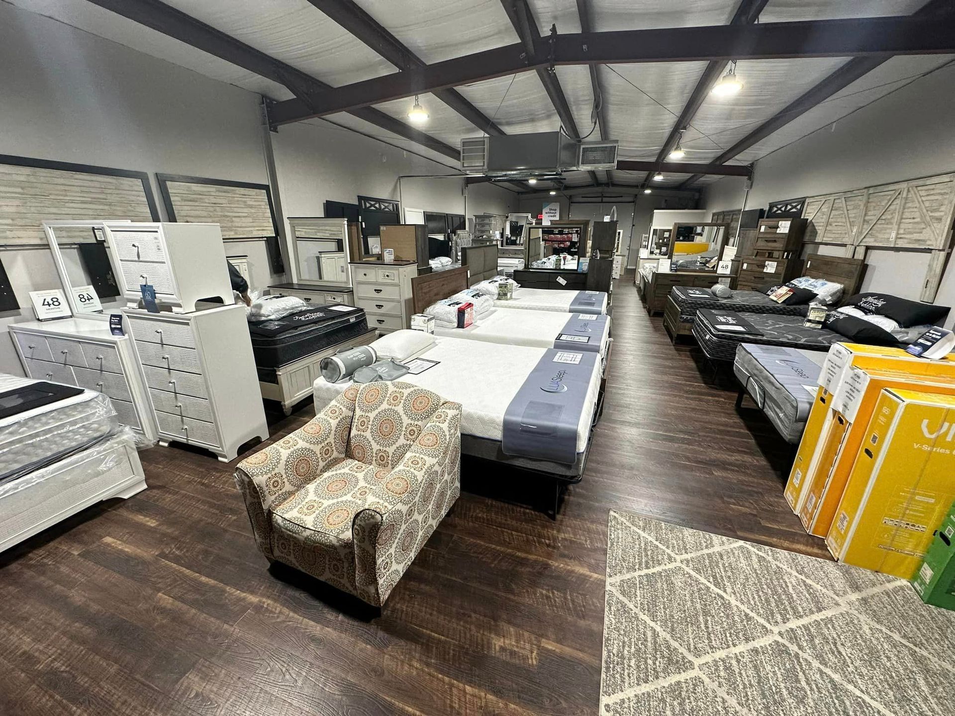 Furniture store interior with displayed beds, chests, and an upholstered chair.
