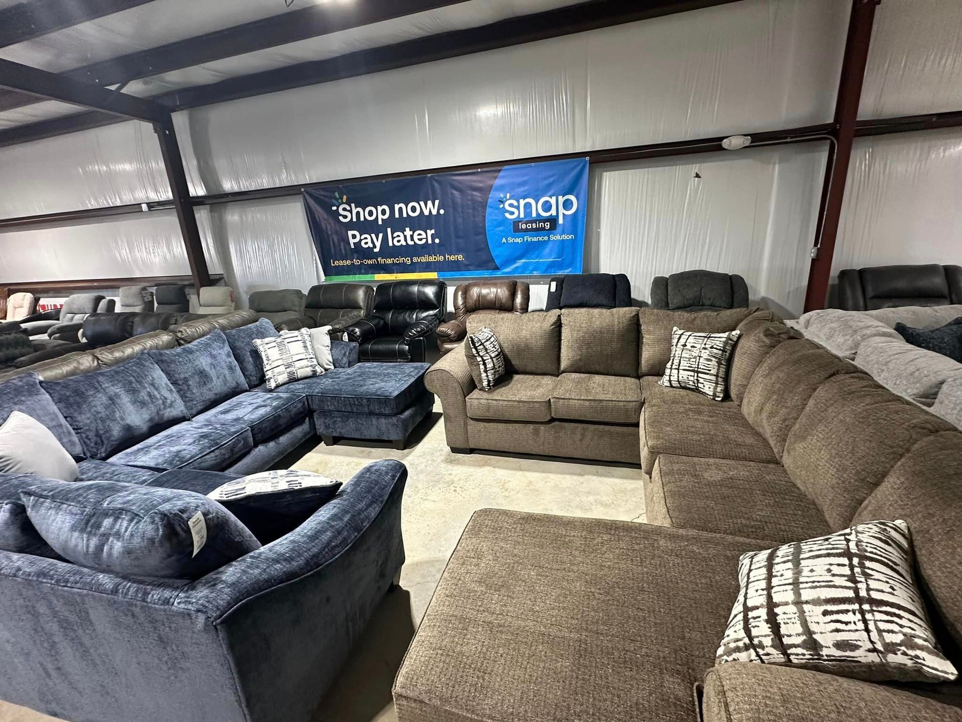 Sofas in a warehouse; various colors and styles displayed with a Snap Finance sign.