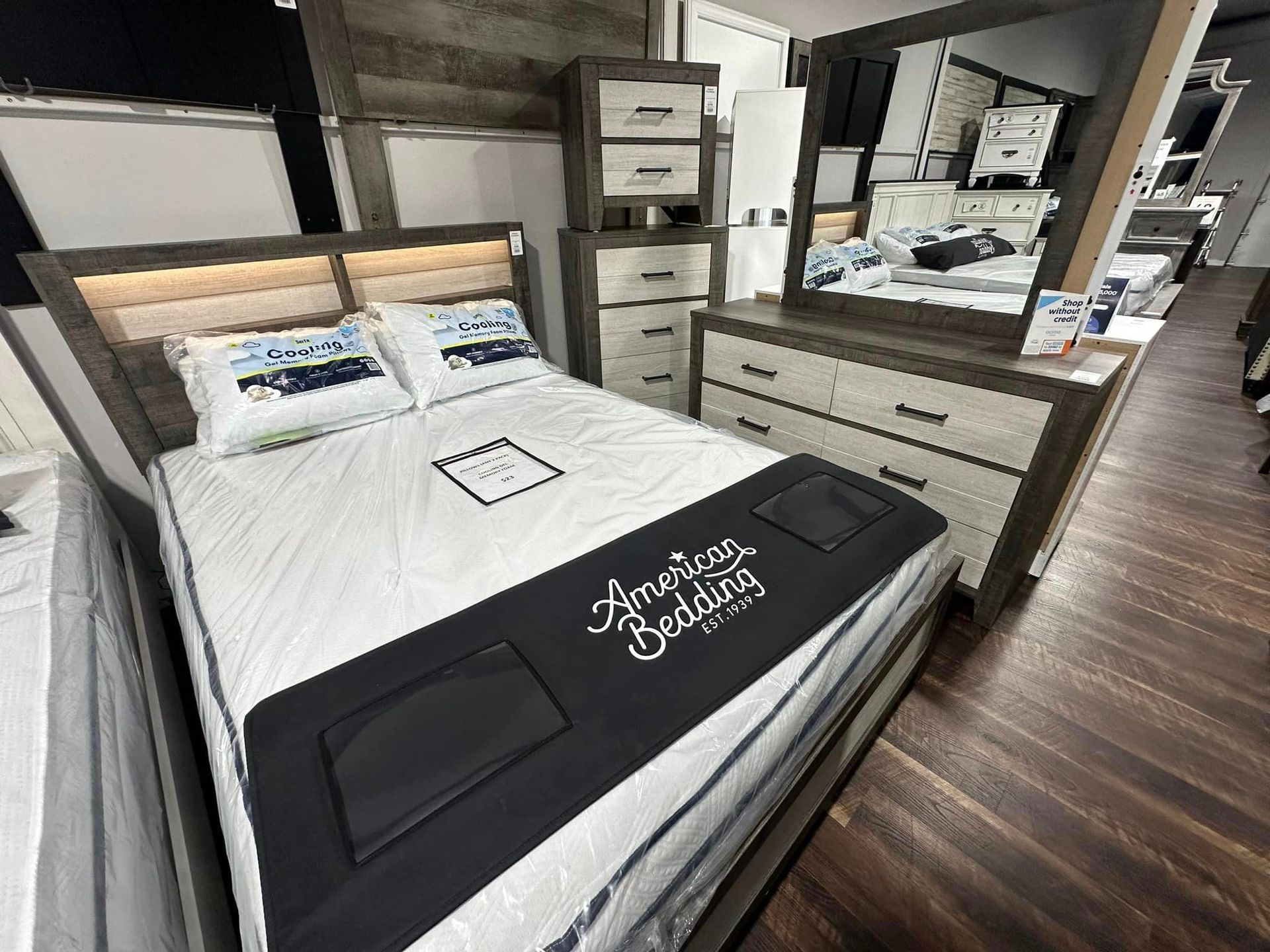 A modern wooden bedroom set featuring a bed with integrated headboard lighting, a matching chest, and a dresser with mirror.