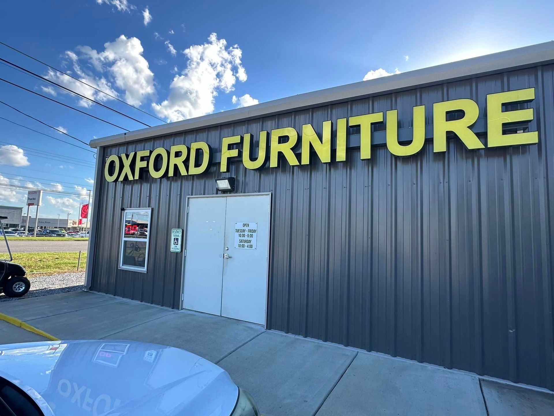 Oxford Furniture storefront with large yellow sign on a dark building under a blue sky