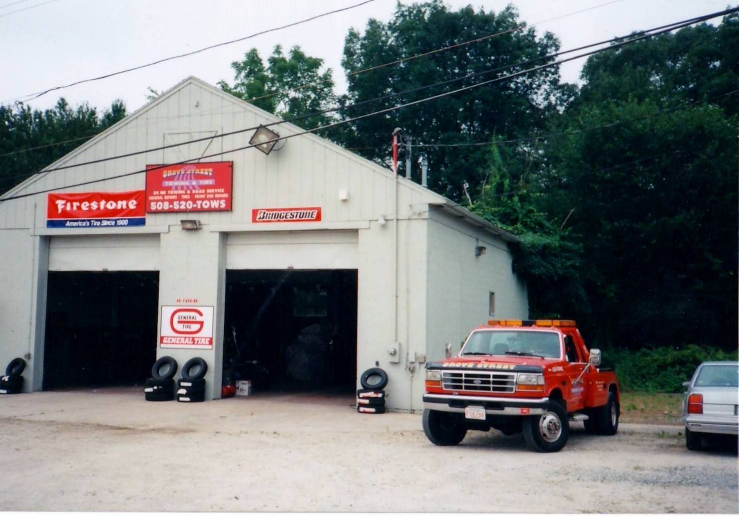 Firestone auto repair shop with an orange tow truck parked outside