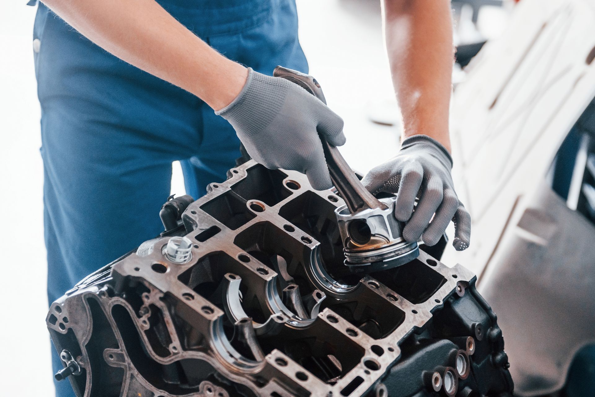 Mechanic in gray gloves inspecting a car engine block in a garage