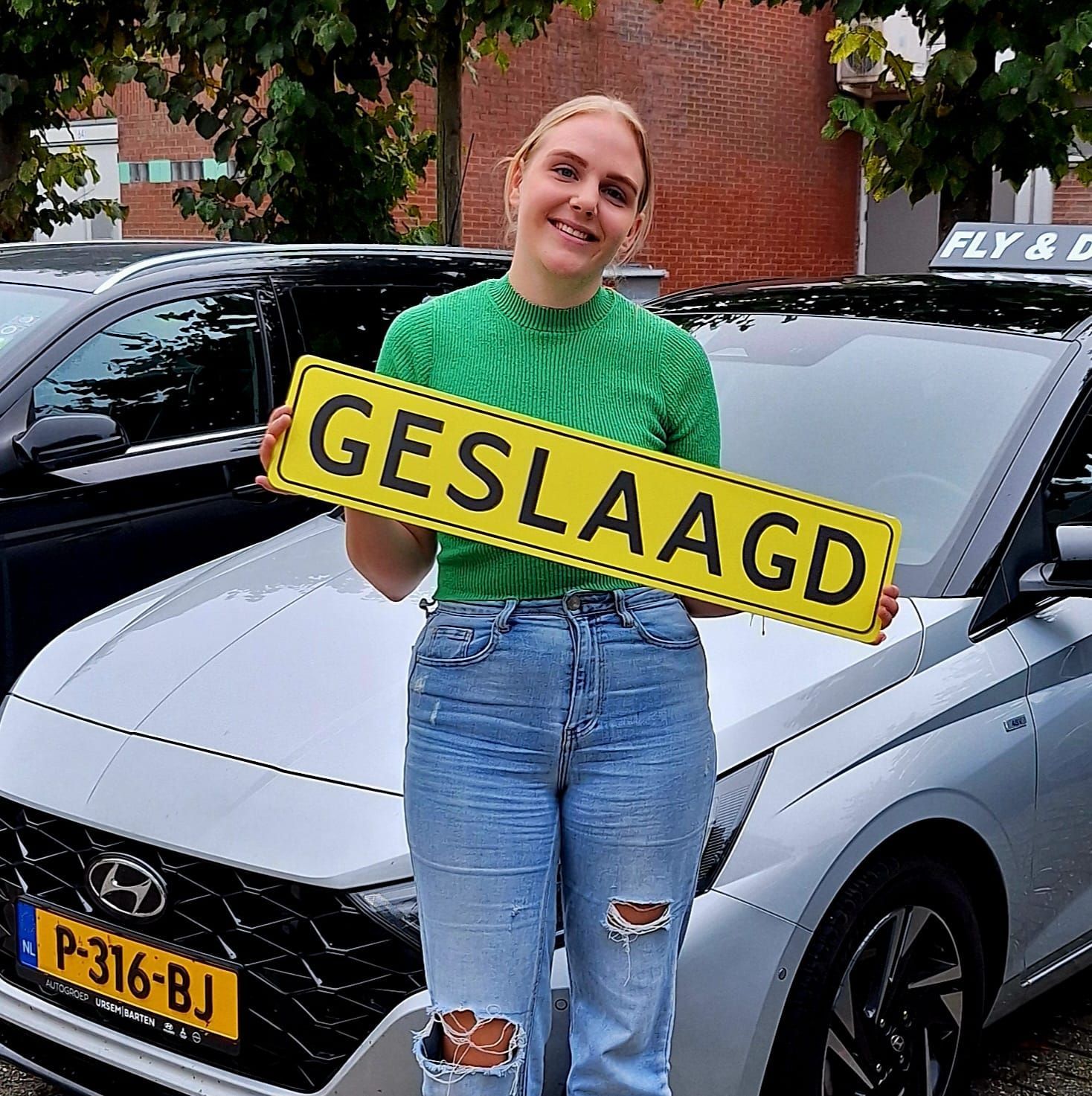 Een lachende persoon in een groen shirt houdt een bord met de tekst