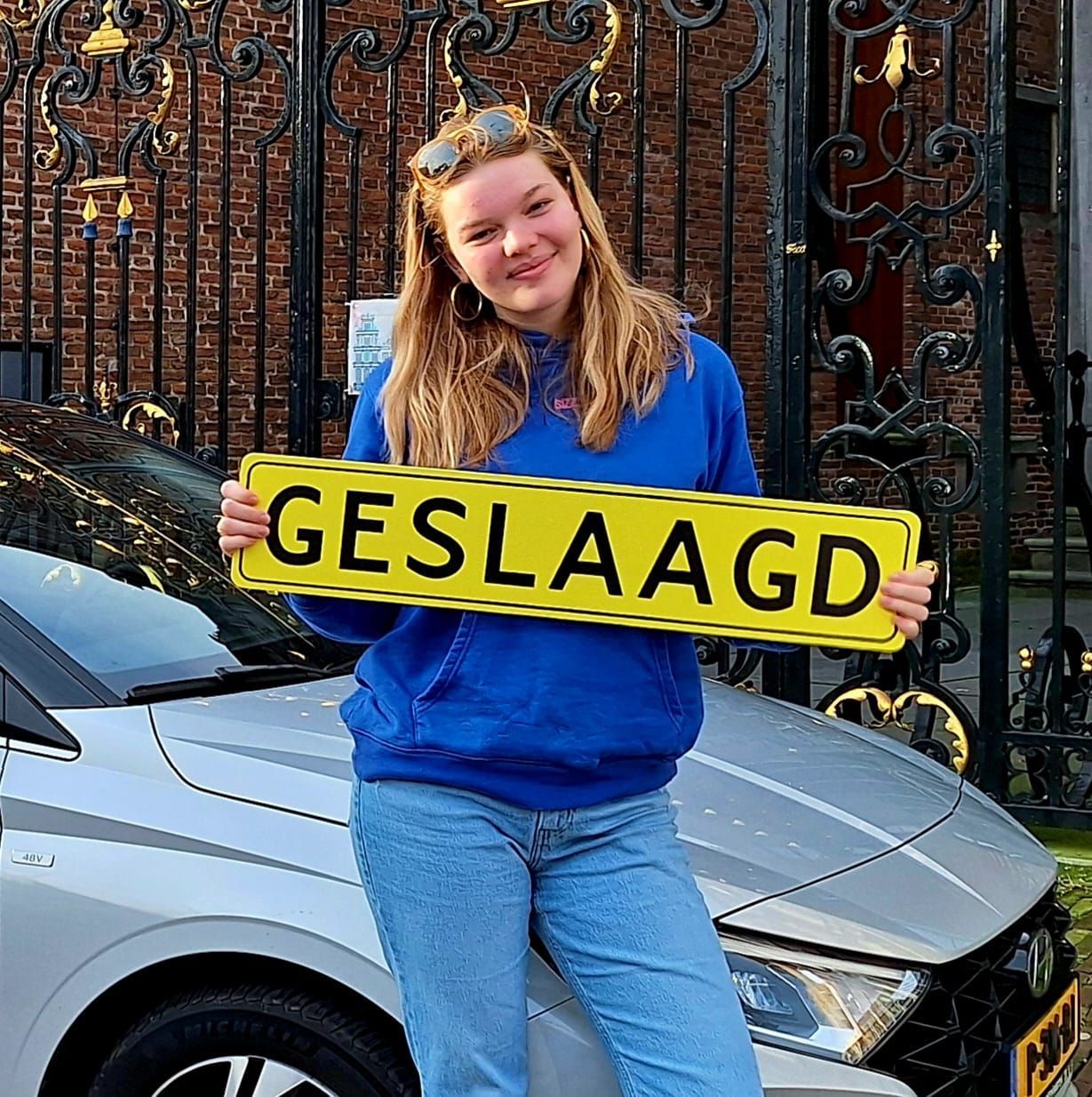 Een persoon glimlacht en houdt een geel bord vast met de tekst