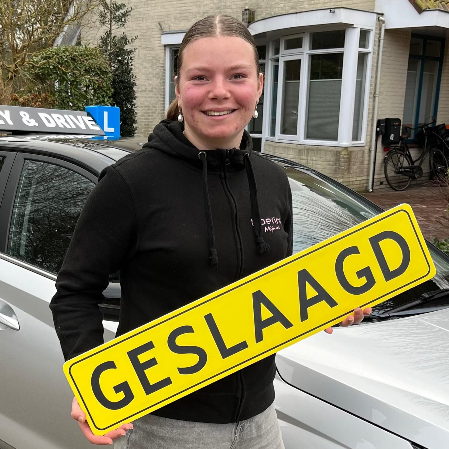 Een persoon in een zwarte hoodie houdt een geel