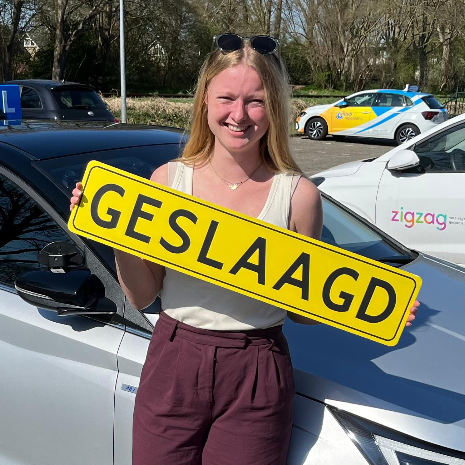Een vrouw staat lachend naast een auto met een geel