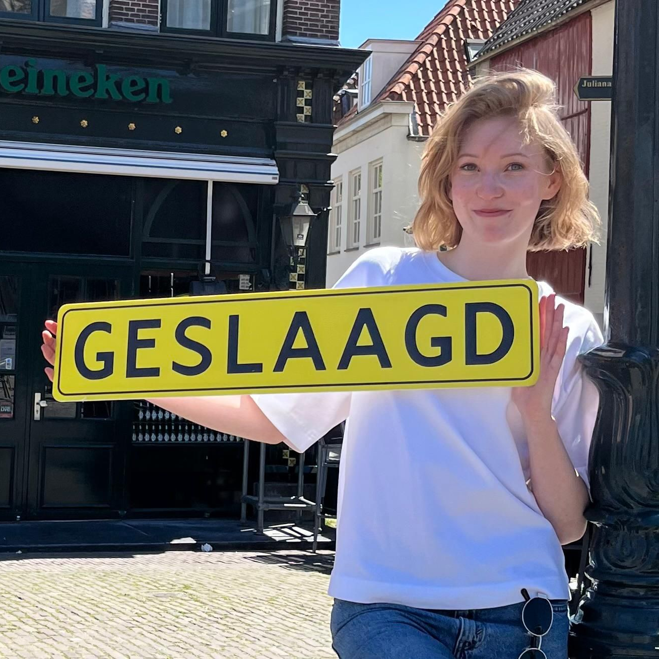 Een persoon houdt een geel bord vast met de tekst