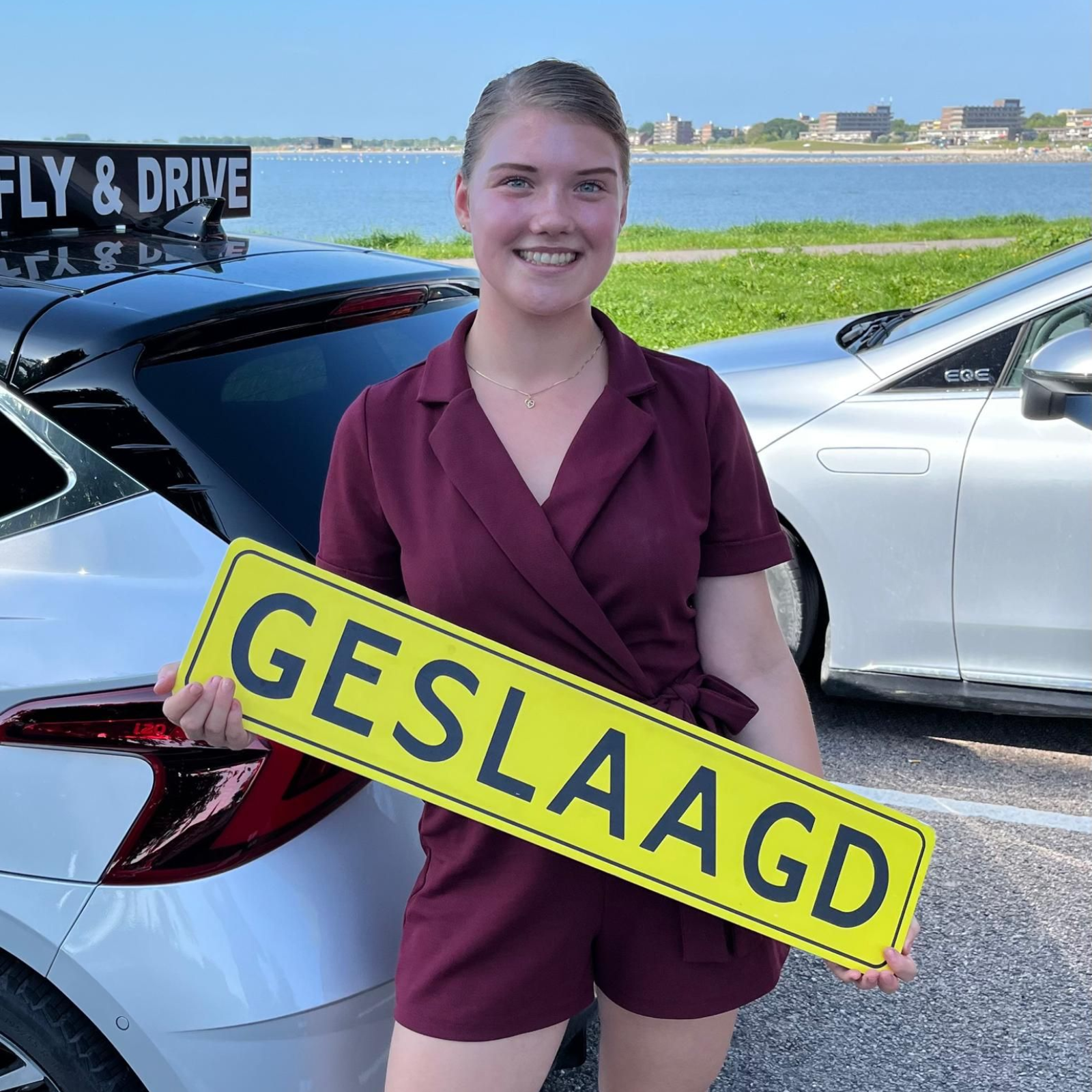 Een lachende persoon in een bordeauxrode overall houdt een geel