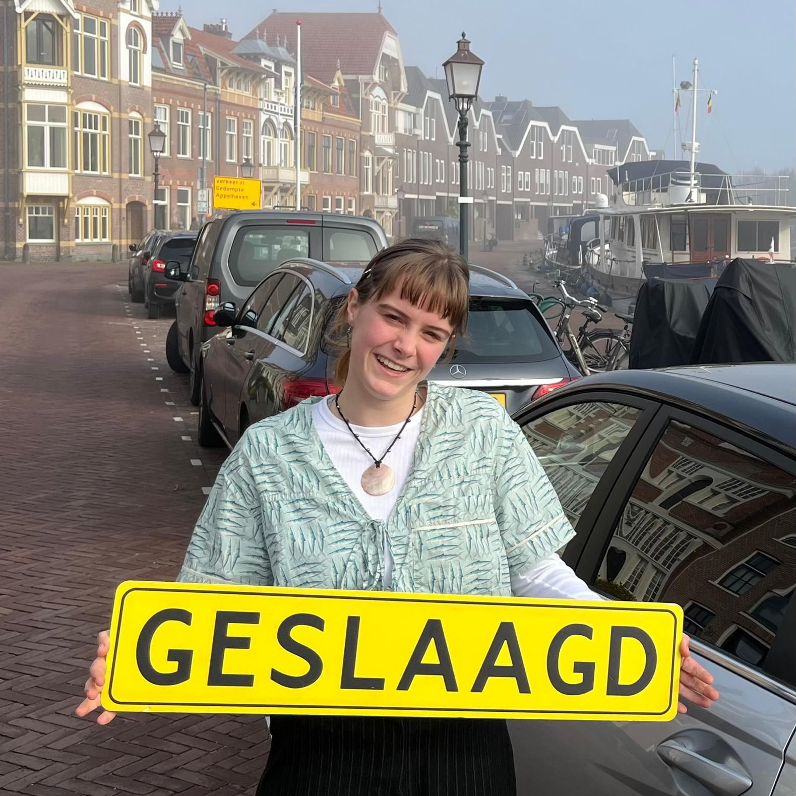 Een lachend persoon houdt een geel bord vast met de tekst