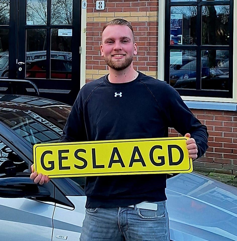 Een man staat naast een auto en houdt een geel