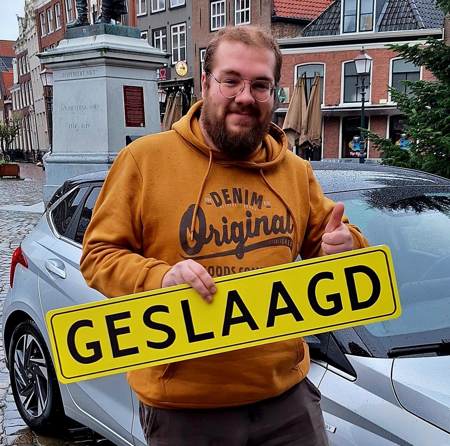 Een persoon in een mosterdkleurige hoodie houdt een geel