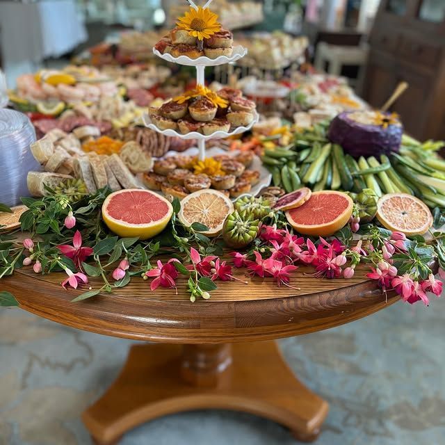 A wooden table topped with a variety of food and flowers.