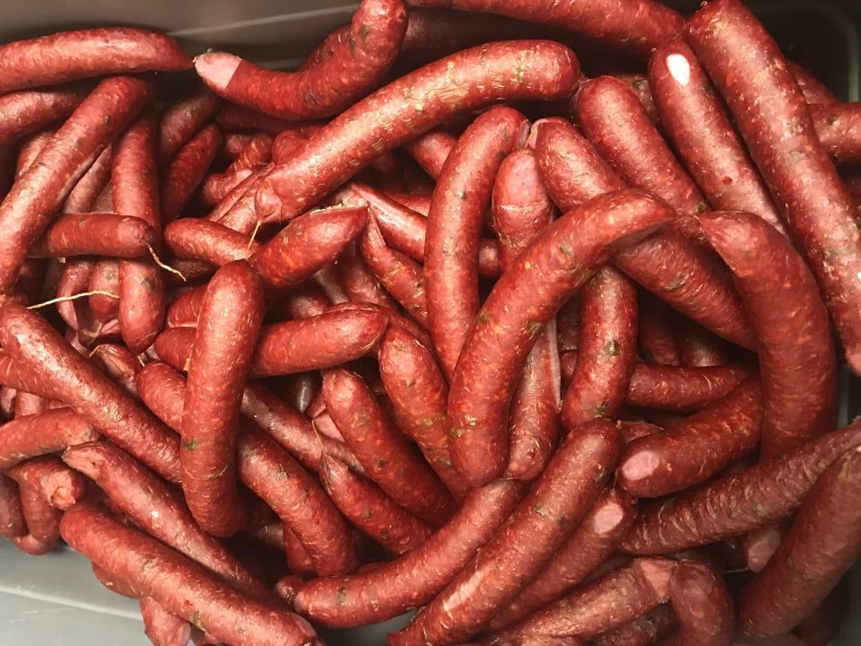 A pile of red sausages in a plastic container