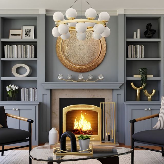 Elegant gray living room with a lit fireplace, gold chandelier, built-in shelves, and two black chairs