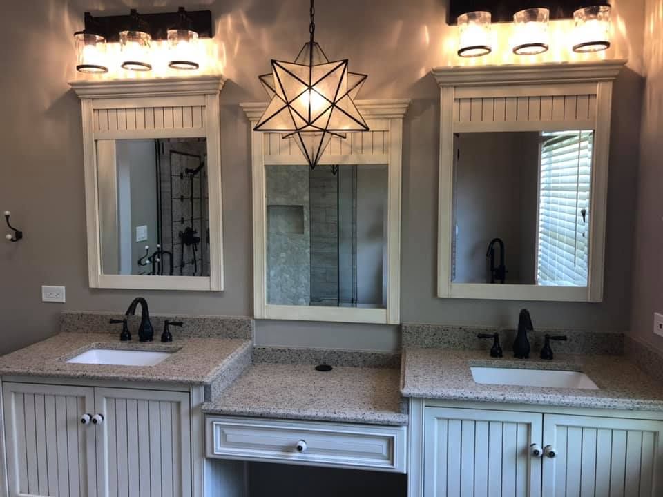 Double vanity bathroom with two mirrors, sconces, granite counters, and a star pendant light.