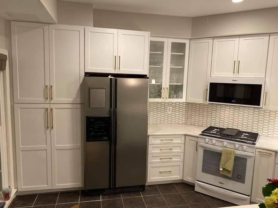 Bright modern kitchen with white cabinets, stainless steel fridge, and stove under a microwave
