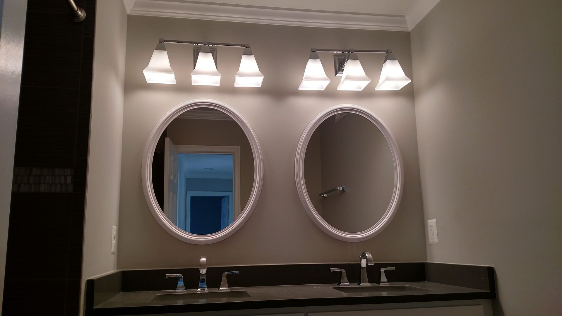 Bathroom vanity with two round mirrors, double sinks, and wall lights above a dark countertop