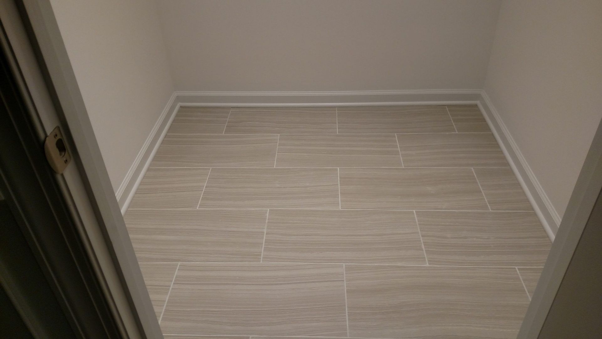 Empty tiled alcove with beige walls and light wood-look flooring