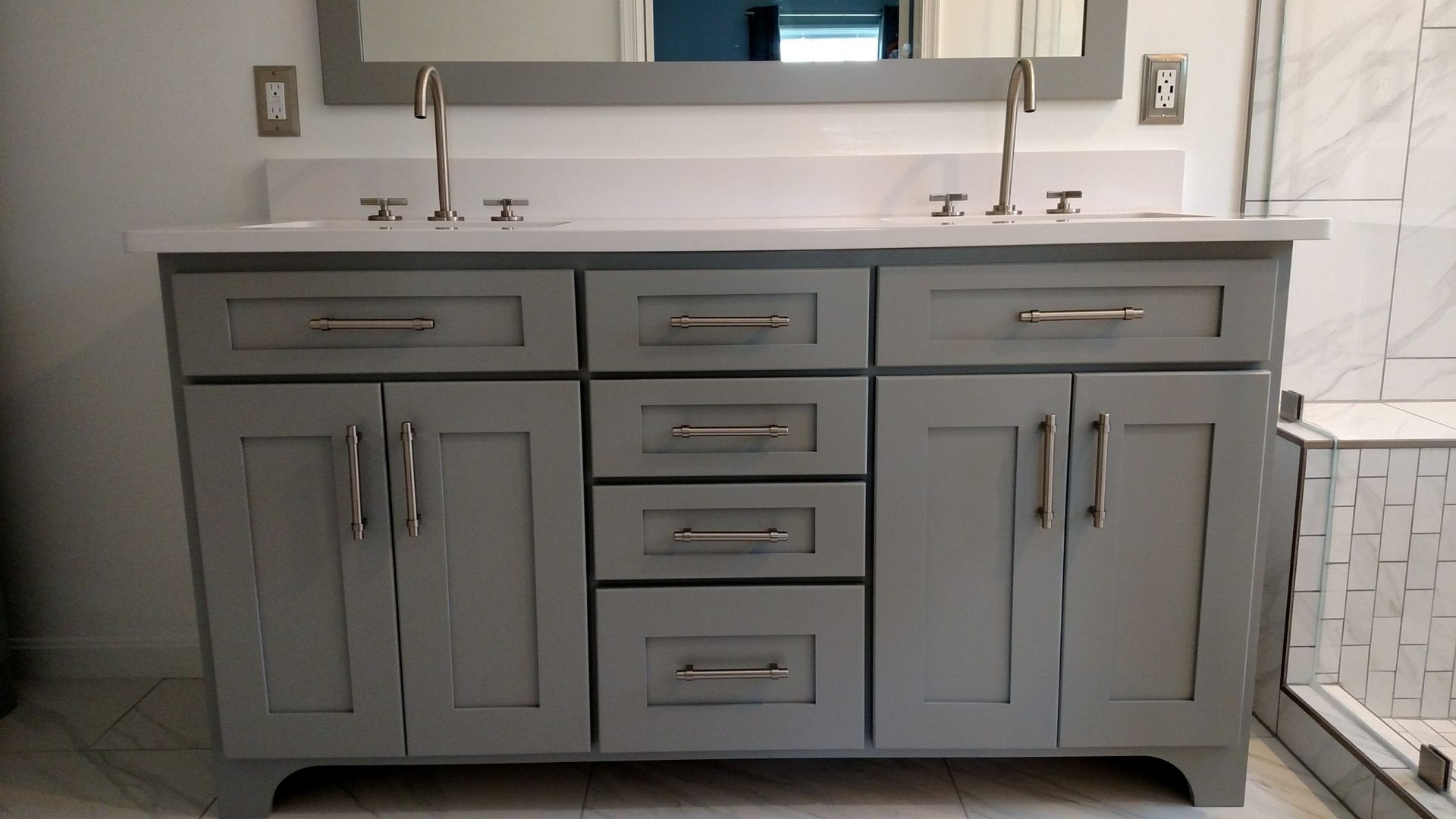 Gray double-sink bathroom vanity with white countertop, mirrors, and chrome faucets