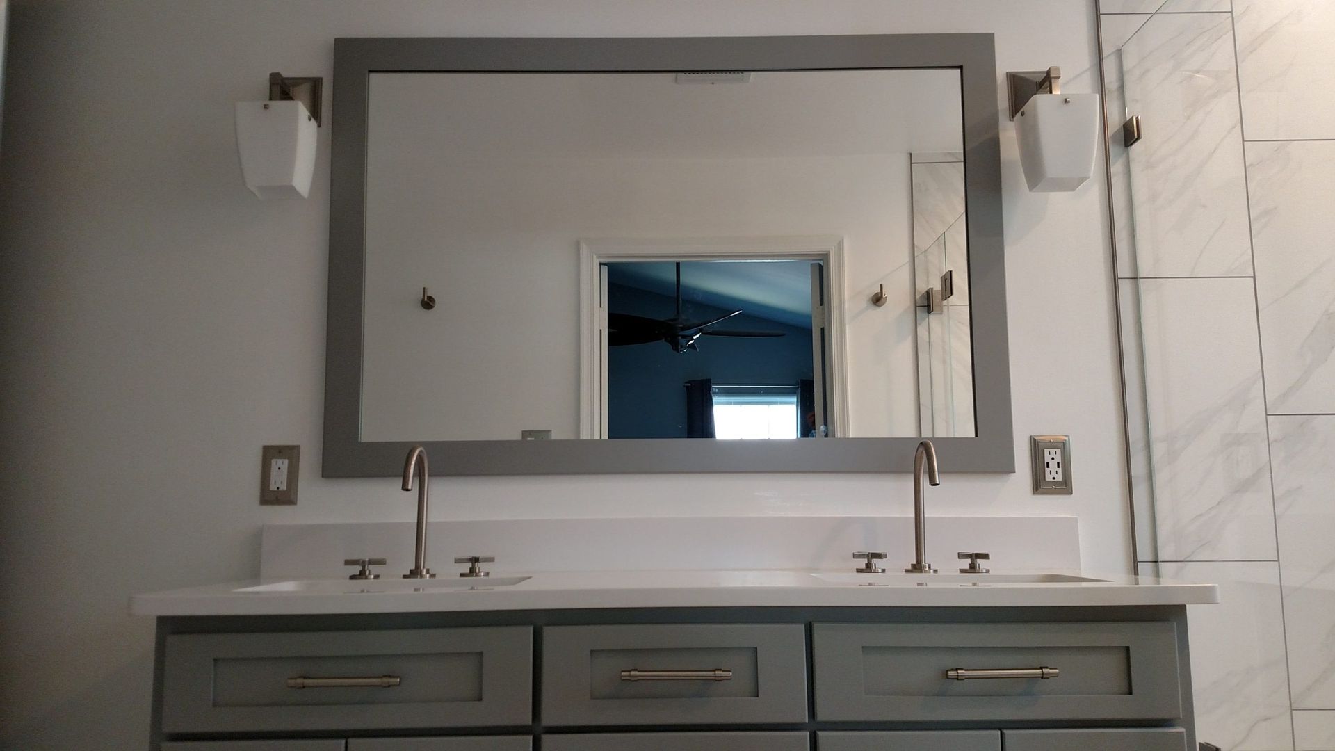 Bathroom vanity with double sinks, large mirror, and wall sconces in a modern gray-and-white room