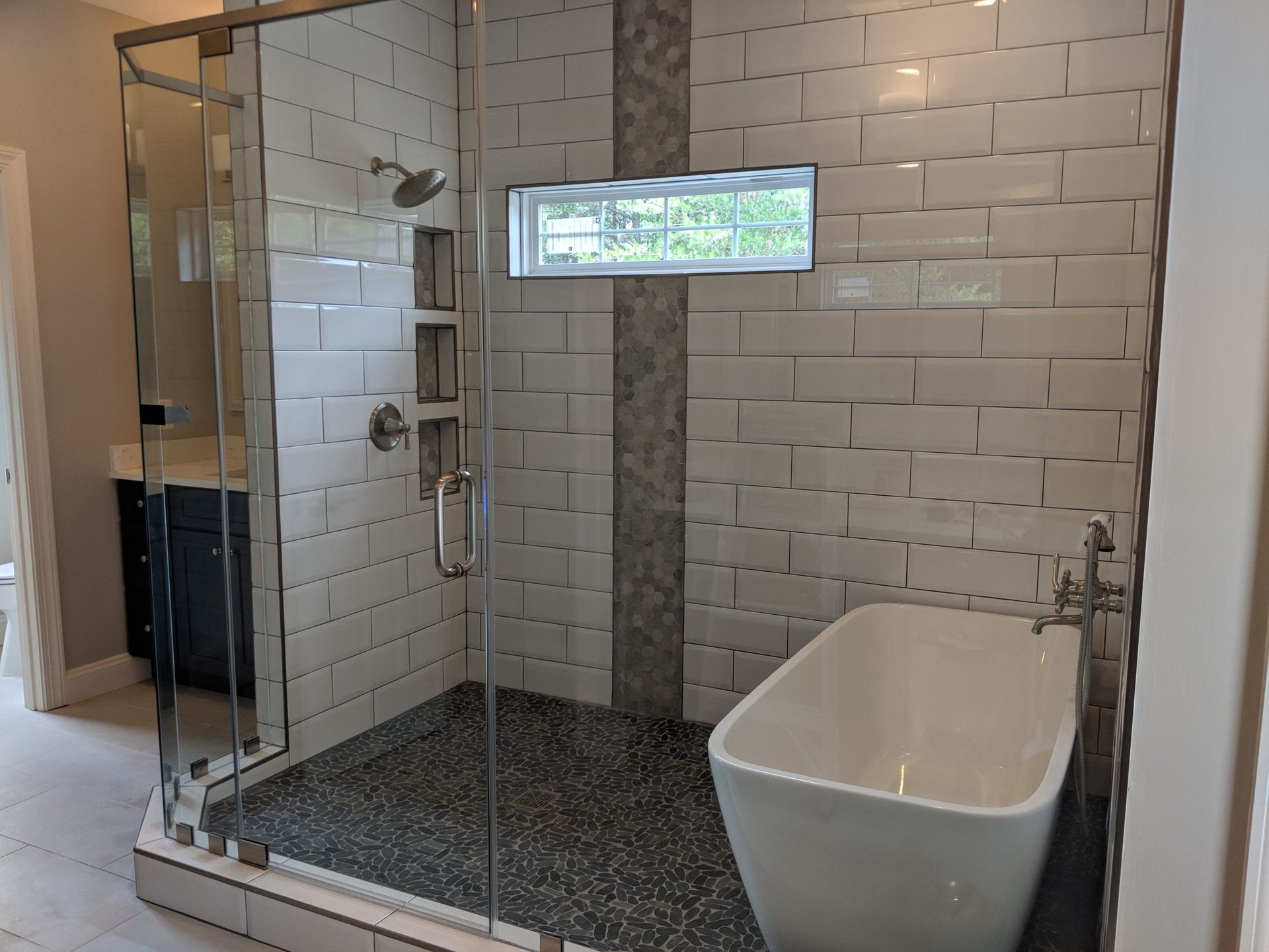 Modern bathroom with glass shower, white subway tile, and freestanding tub