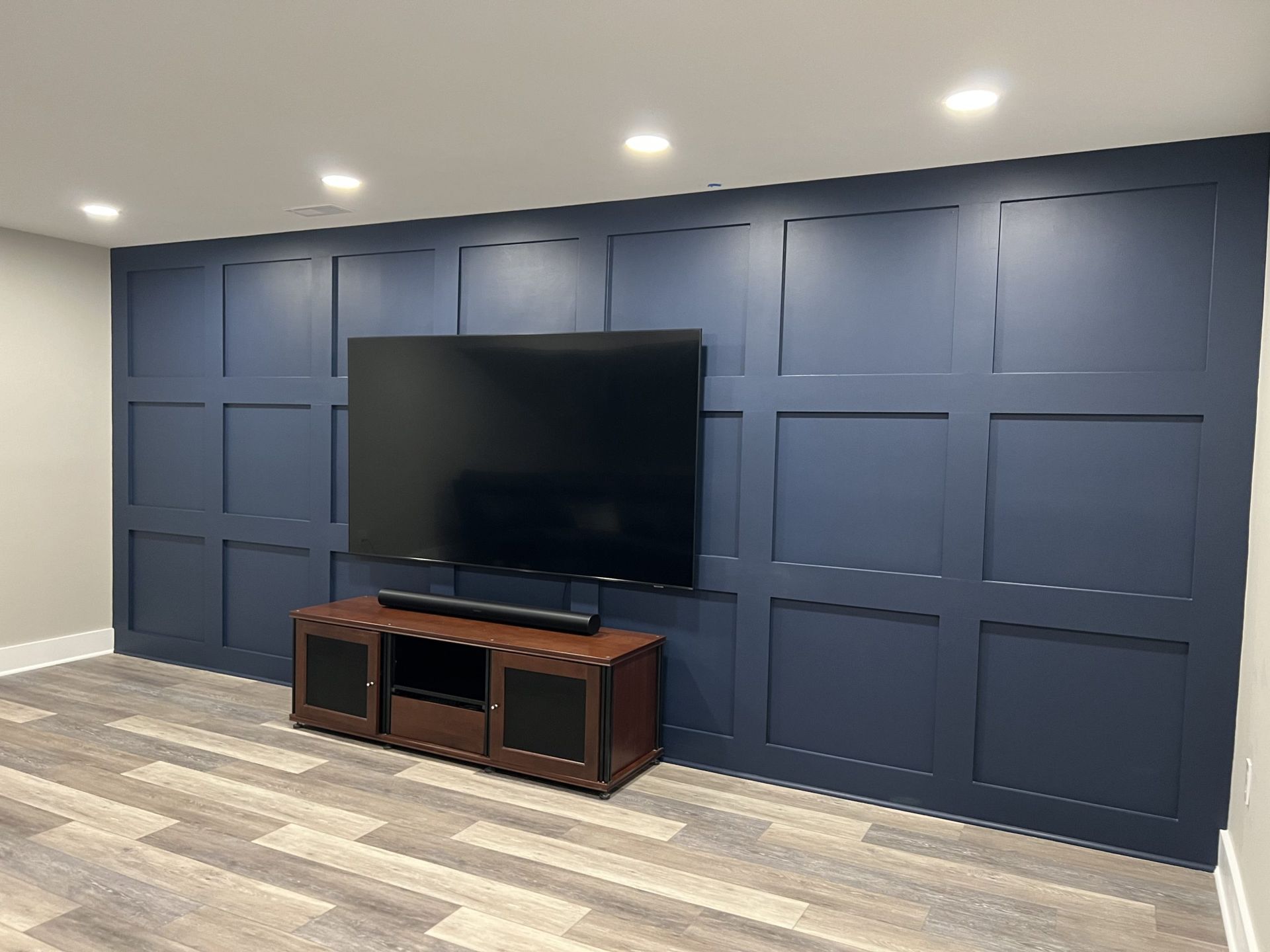 Blue-paneled media wall with a large TV and wooden stand in a modern room