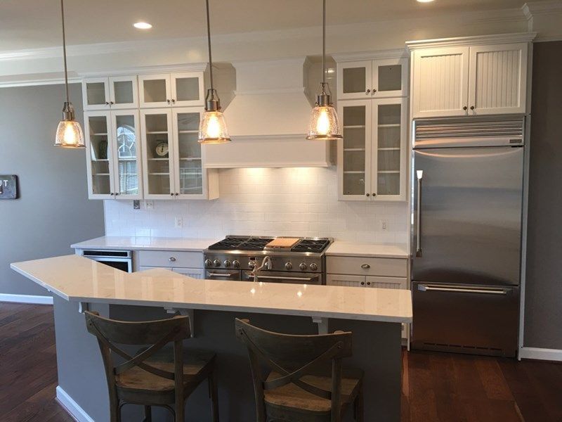 Modern kitchen with white cabinets, stainless-steel appliances, island seating, and pendant lights