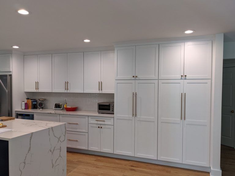 Bright modern white kitchen with cabinets, marble island, and recessed ceiling lights