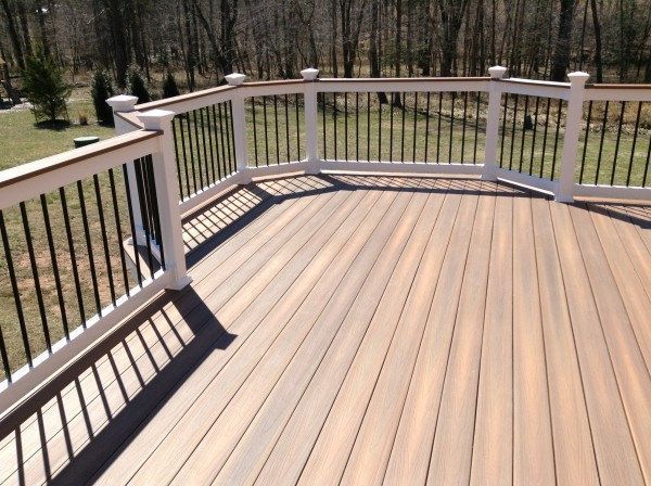 Wooden deck with white railings overlooking a wooded yard on a sunny day
