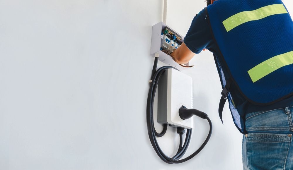 Electrician Working on Electrical Panel, EV Charger Installed on White Wall — DC Active Electrical in Brisbane, QLD