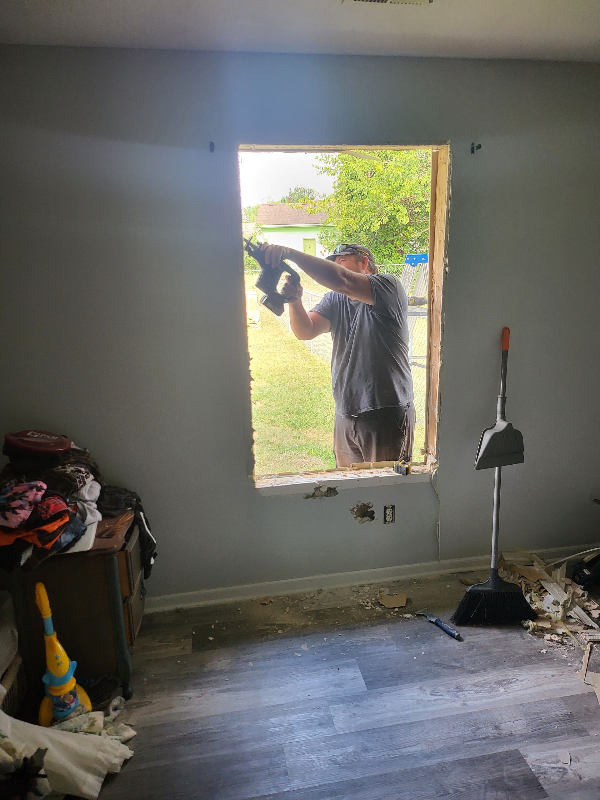A man is cutting a hole in a window in a room.
