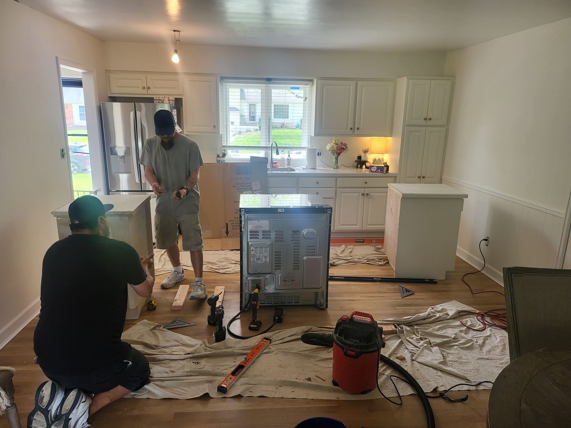 Two men are working on a kitchen in a house.