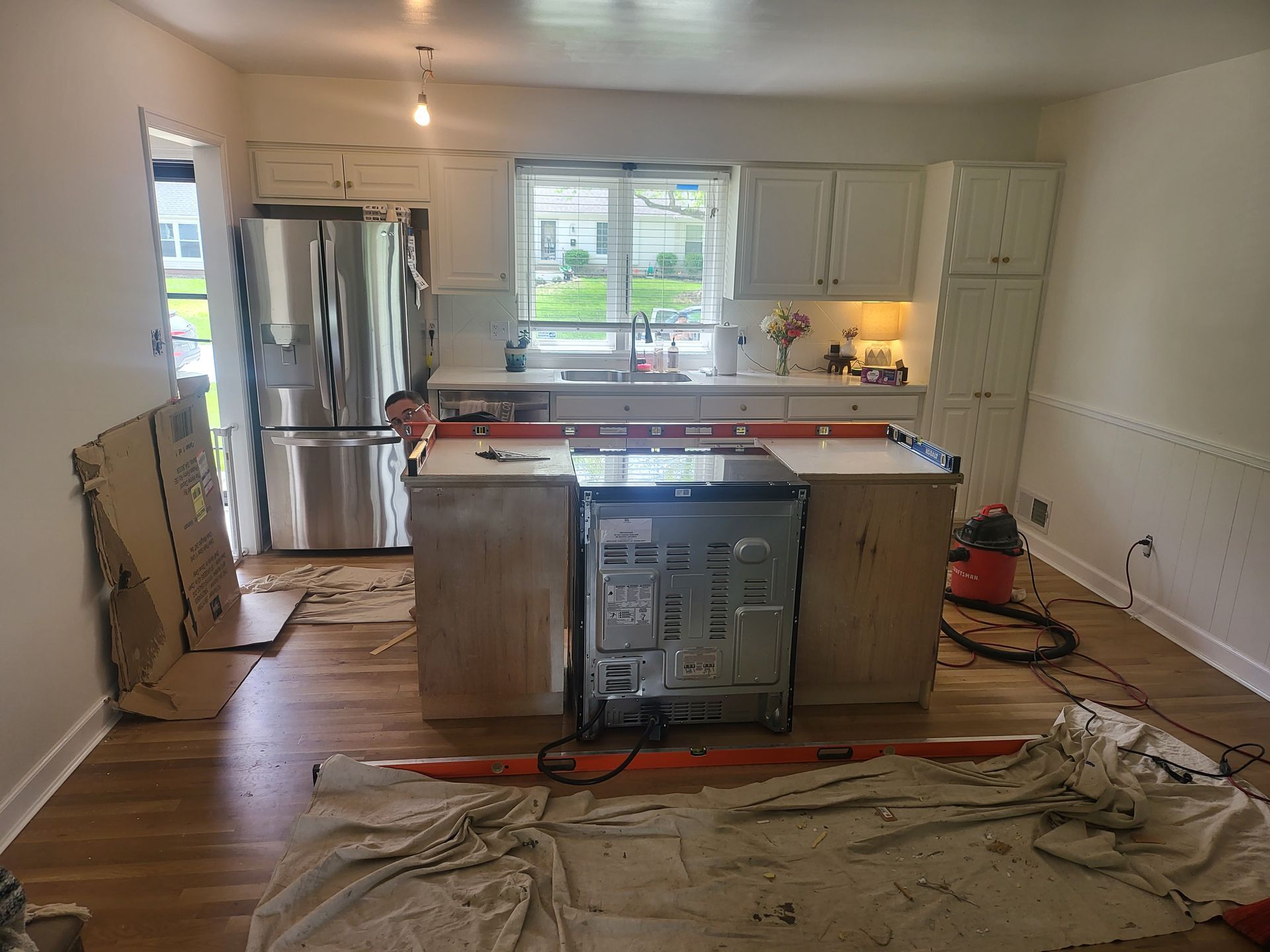 A kitchen is being remodeled with stainless steel appliances and wooden cabinets.