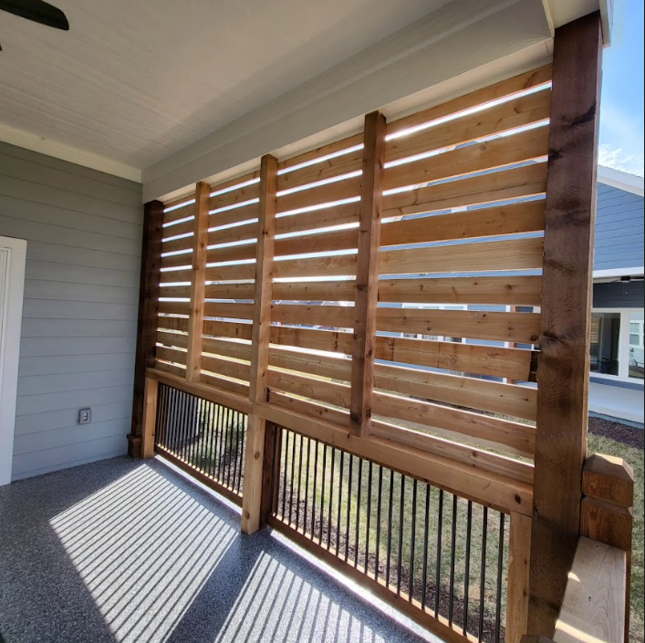 A porch with a wooden fence and a ceiling fan