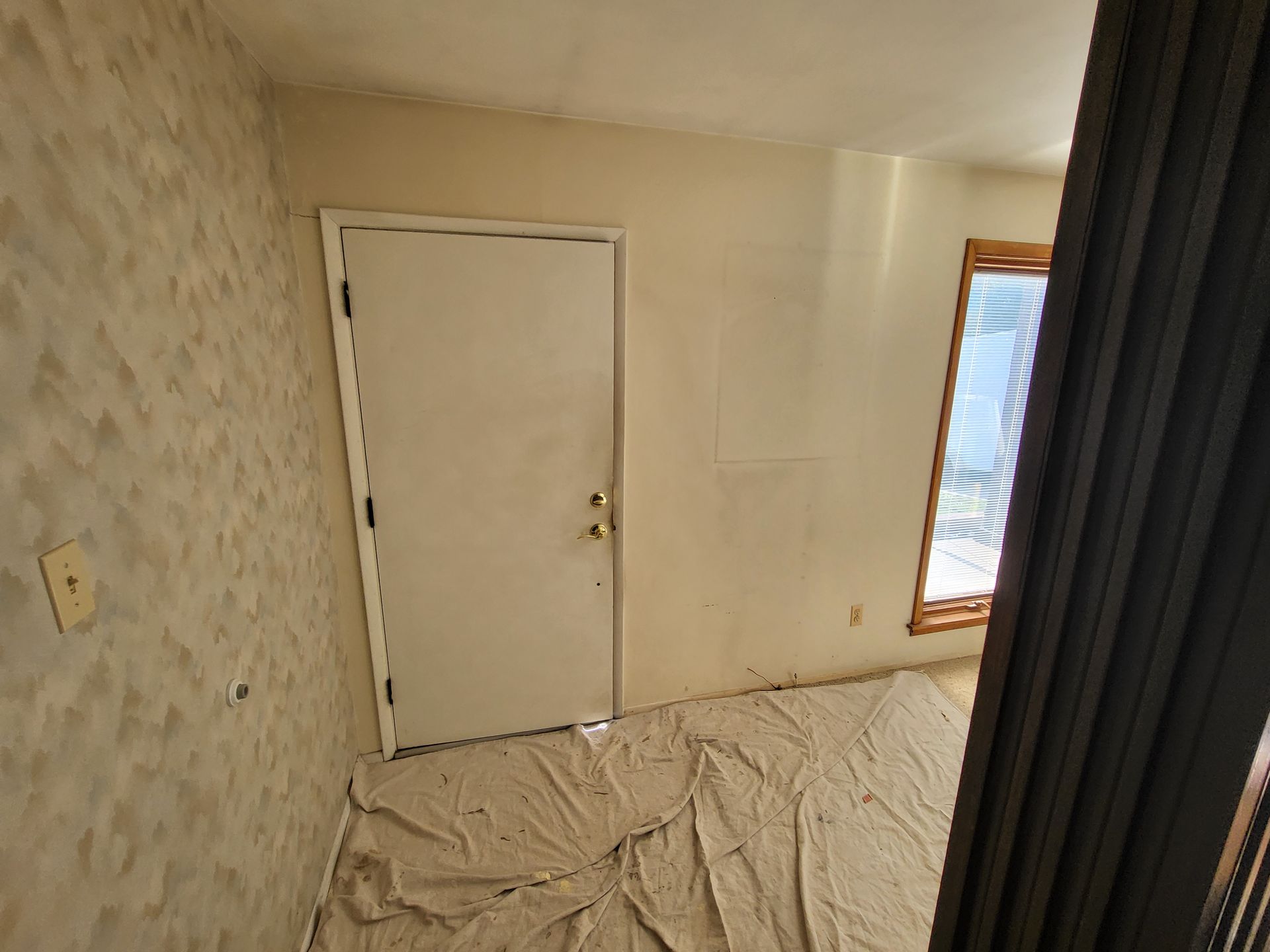 An empty room with a white door and a window.