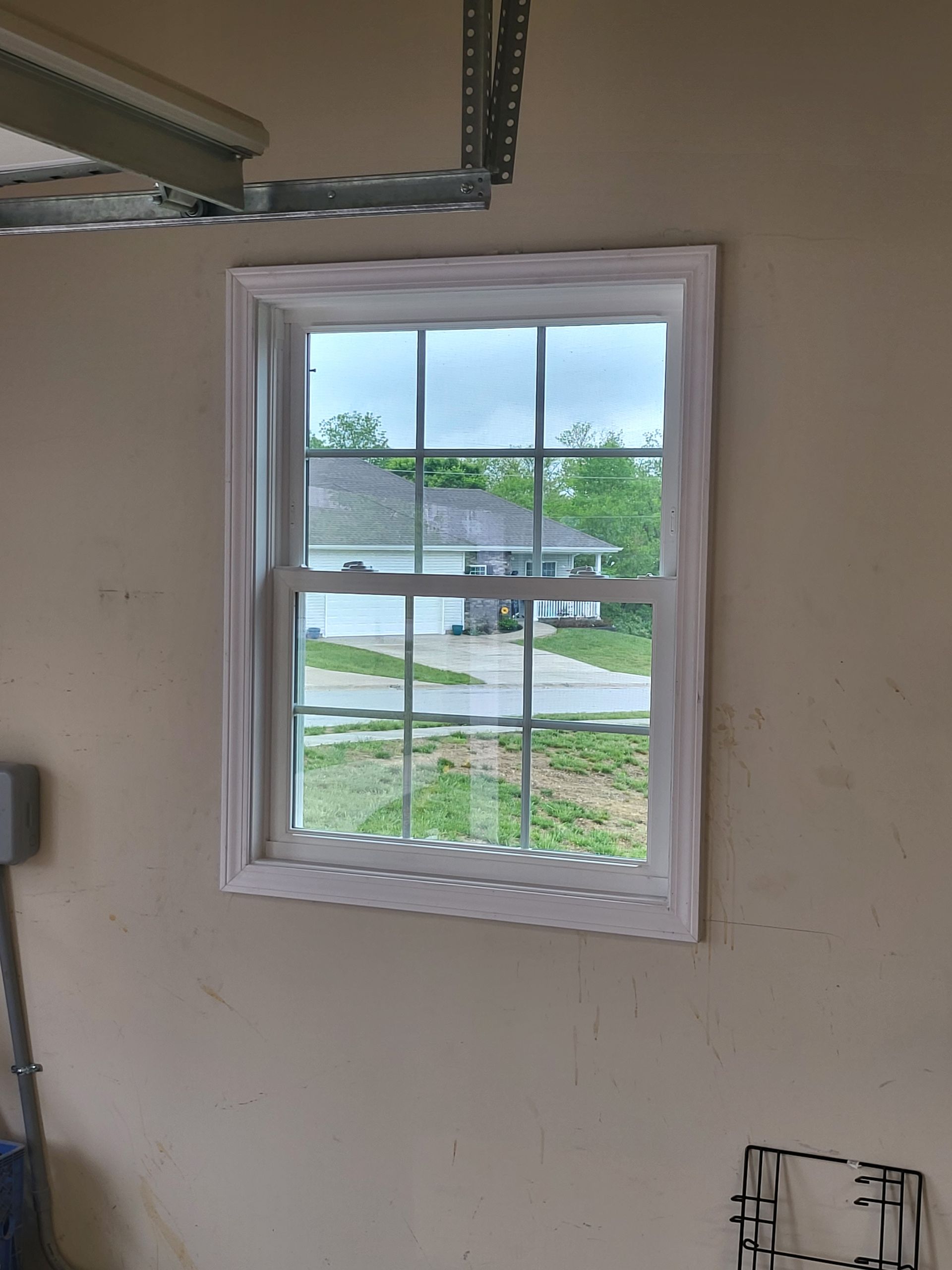 A window in a garage with a view of a house.