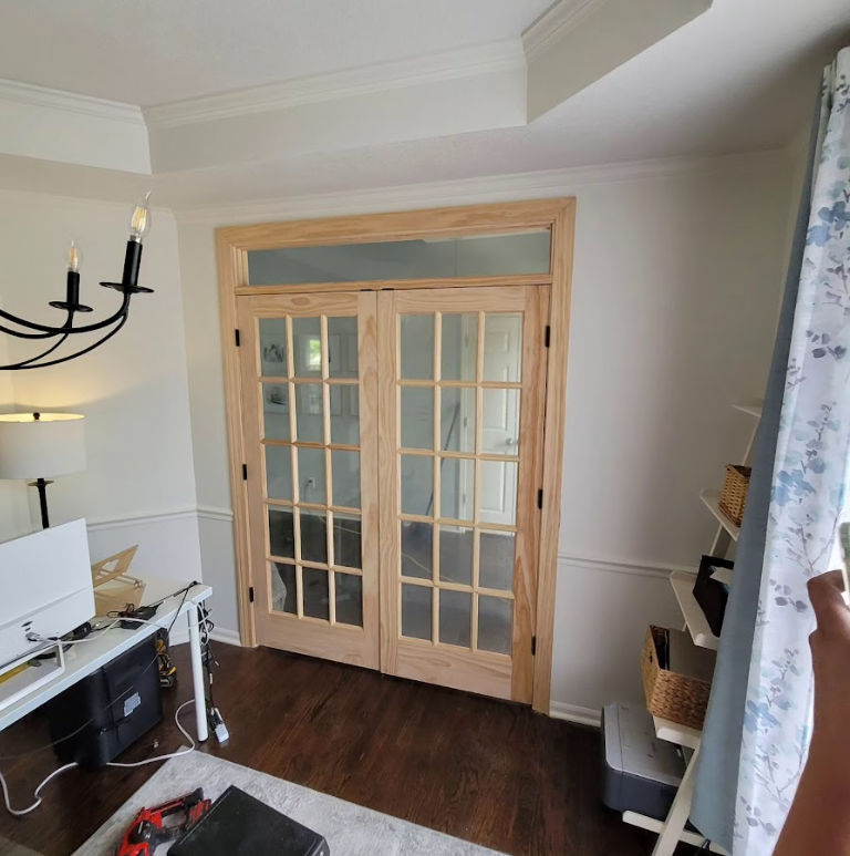 A living room with french doors and a desk