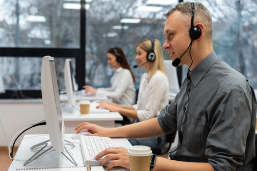 Un homme portant un casque est assis à un bureau devant un ordinateur.