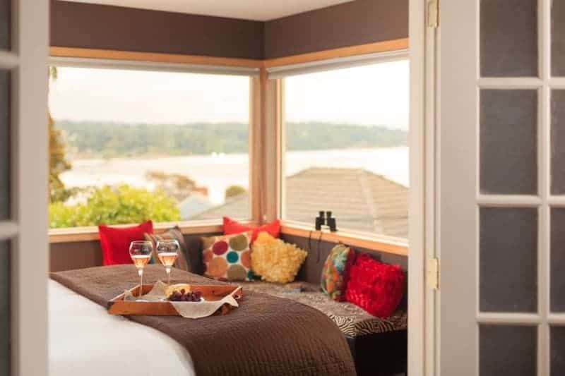 A bedroom with a bed and a window with a view of the ocean.
