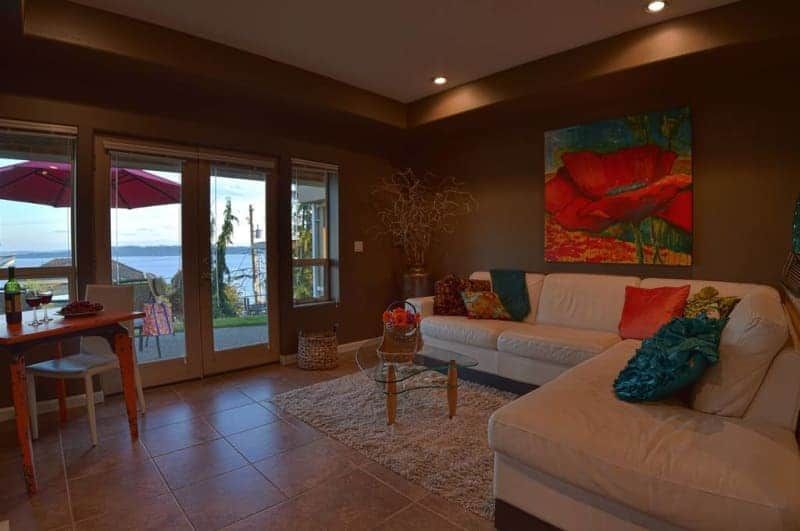 A living room with a couch , table , chairs and a painting on the wall.