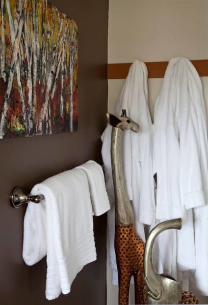 A bathroom with a giraffe and a painting on the wall